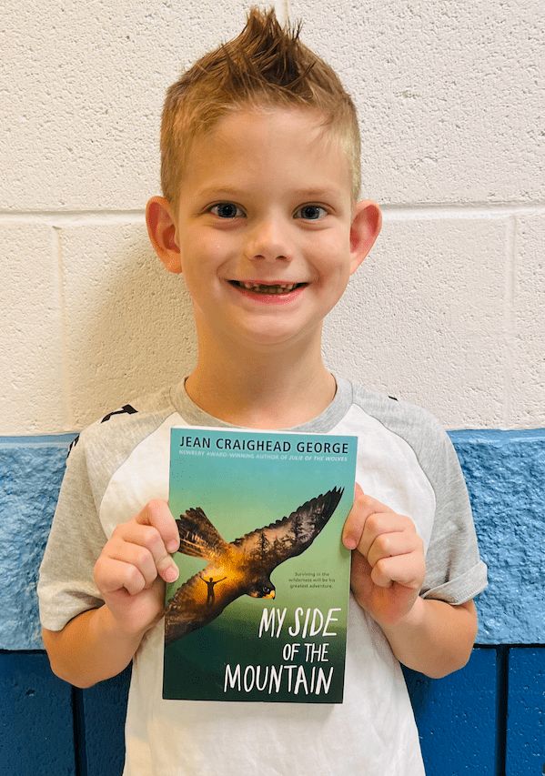 student holding a book received for earning a  praise award